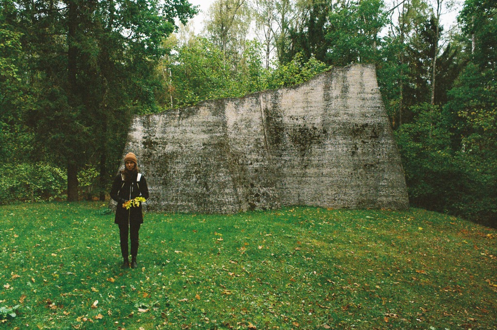 Woman standing in front of outdoor sculpture in wooded area
