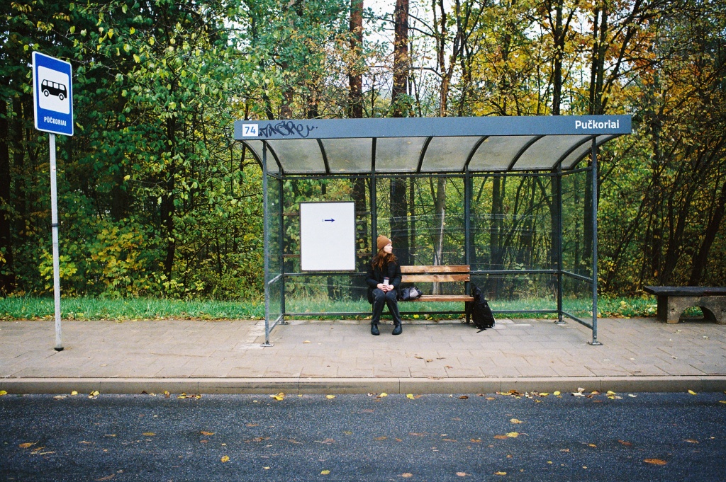 Woman waiting in busstop in wooded area