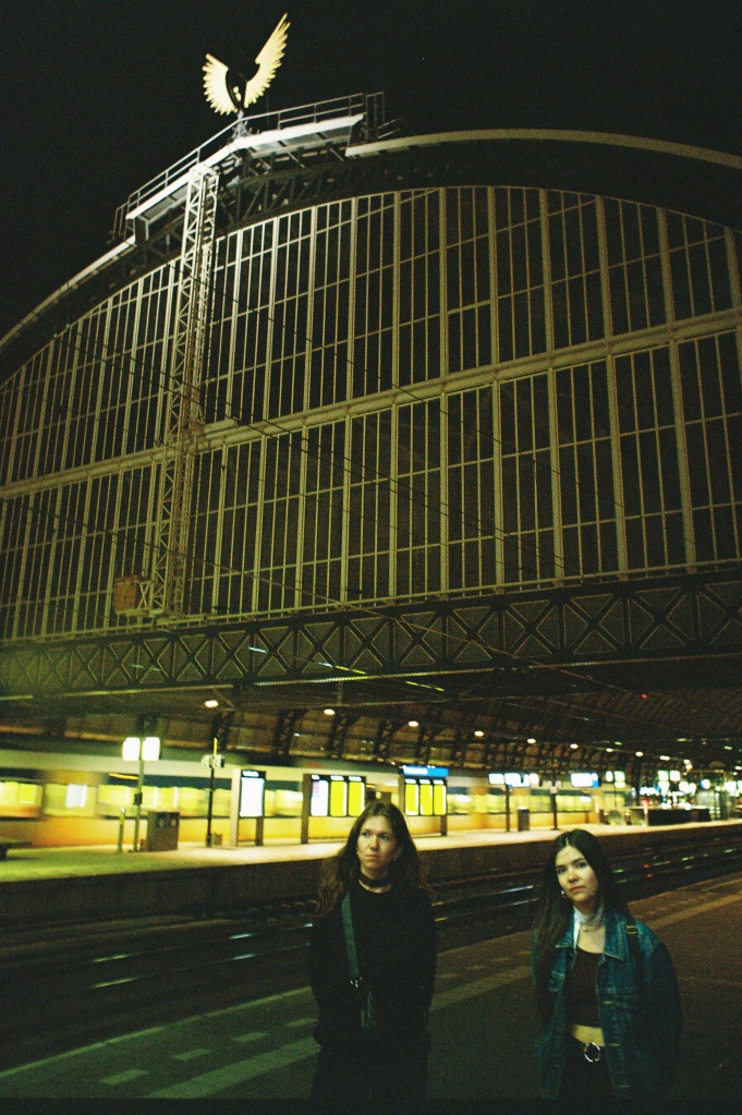 Two women standing in large picturesque train station in Amsterdam